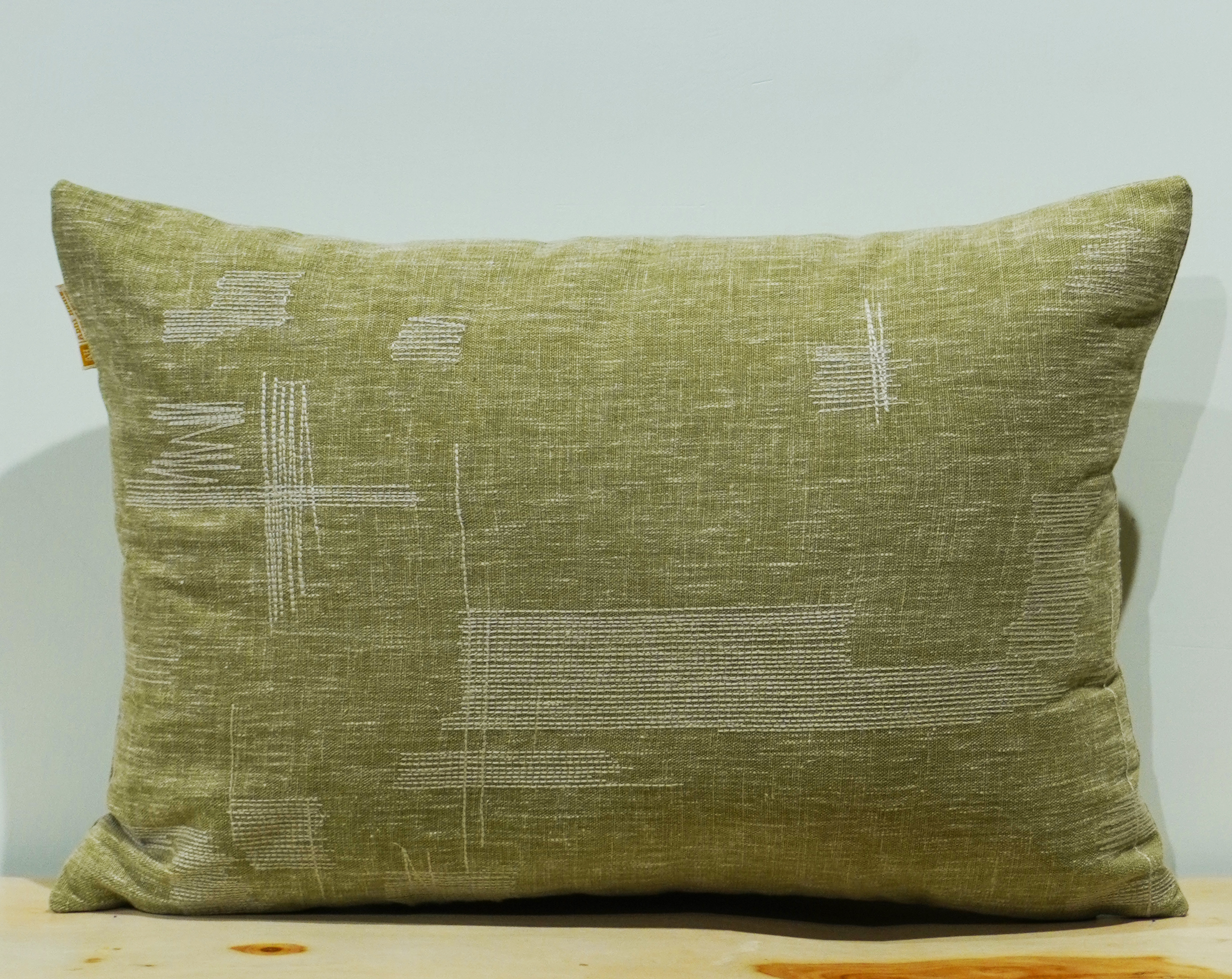 Olive sage green lumbar cushion with white minimalist abstract mark stitch embroidery