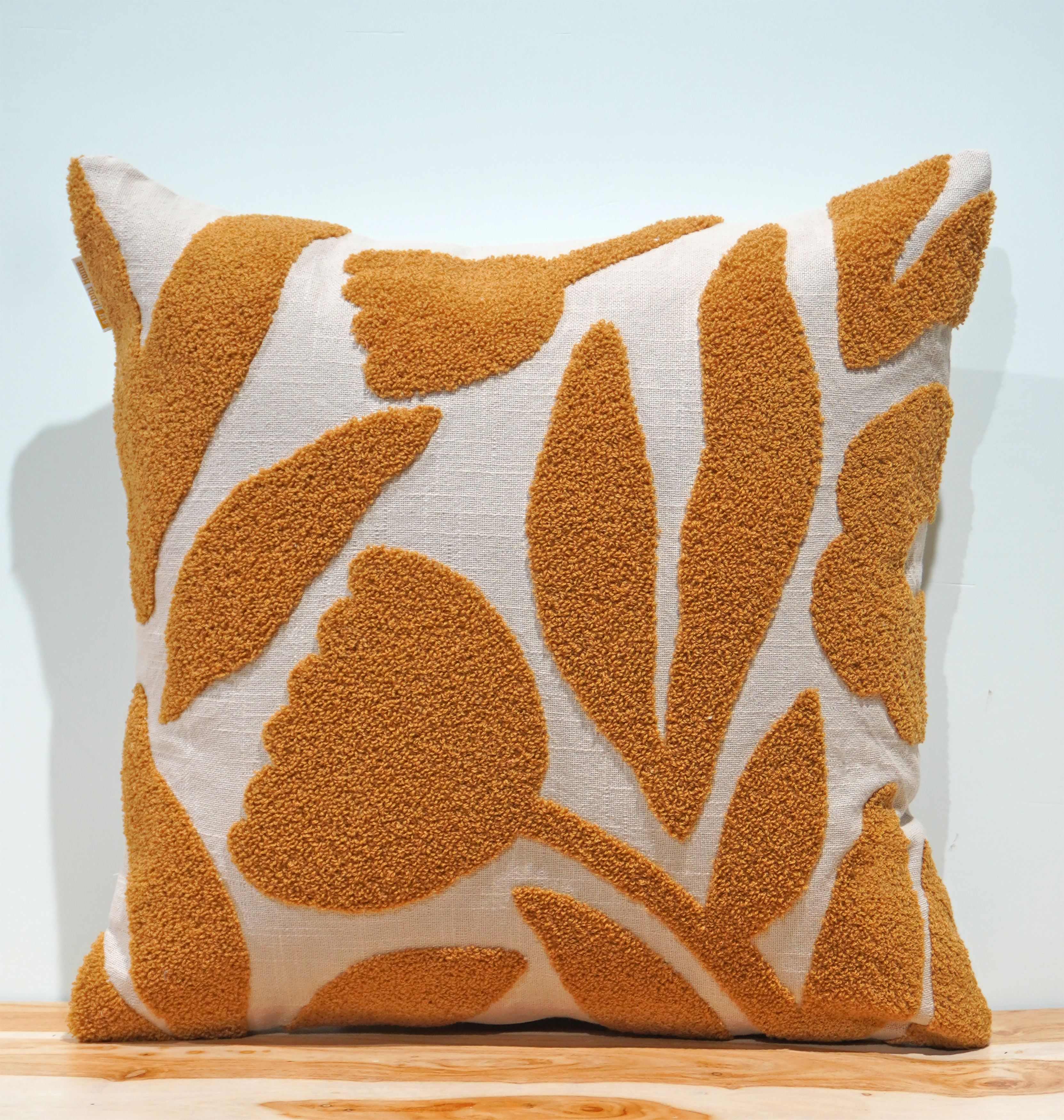Off-white cushion with bold amber mustard botanical tufted embroidery