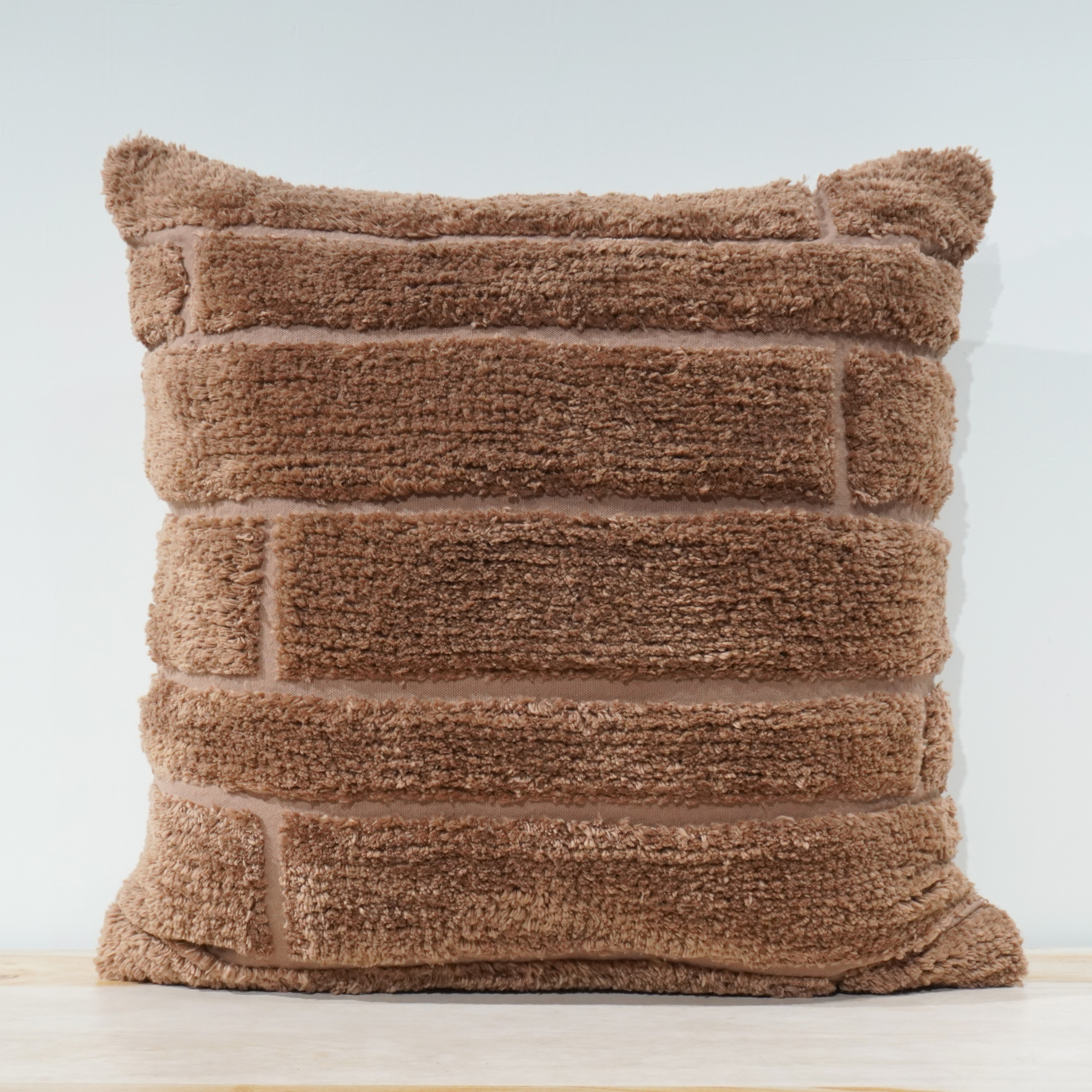 Warm taupe plush tufted square cushion with horizontal brick pattern in chenille