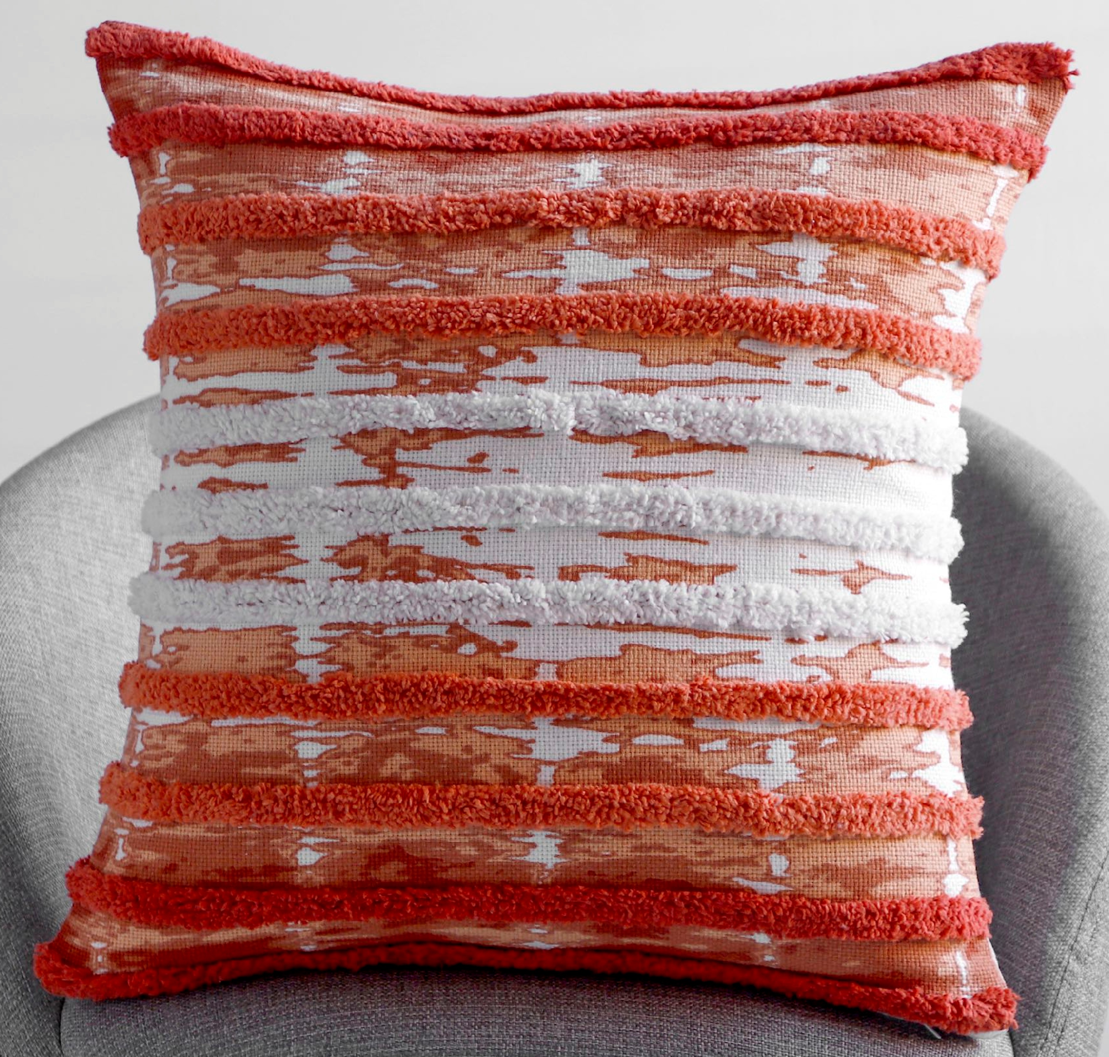 Vibrant coral rust square cushion with horizontal jacquard stripe and tufted chenille inserts